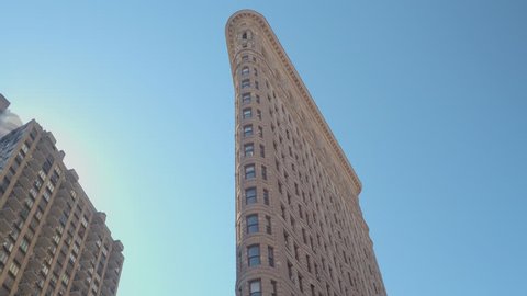 LOW ANGLE VIEW, CLOSE UP: Famous Flatiron iron shaped building with limestone and glazed terracotta facade in New York City, parallel to Fifth Avenue and Broadway streets on beautiful sunny summer day