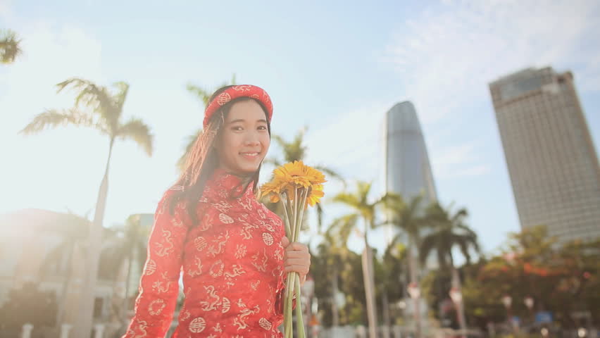 Girl in traditional Vietnamese dress spinning happy with yellow flowers. The mood of delight.