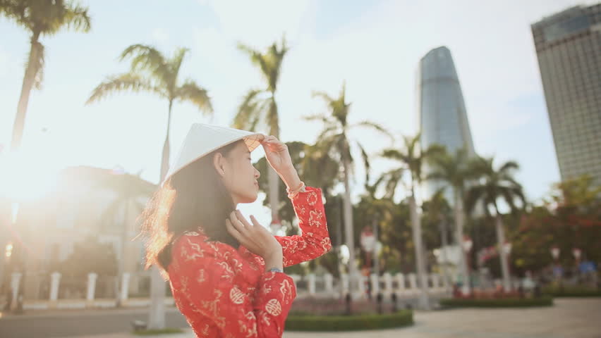 Vietnamese girl puts on a national cap Non La in the rays of the evening