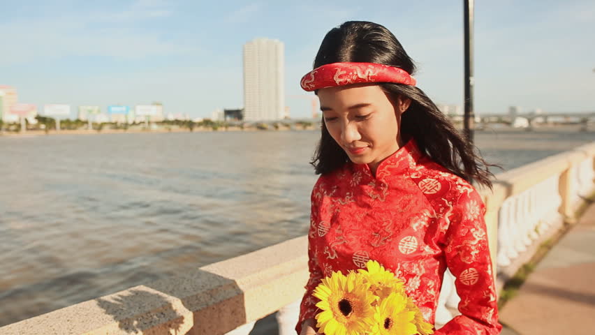 Asian girl in the national costume and the Vietnamese Ao Dai dress walks along the embankment Da Nang