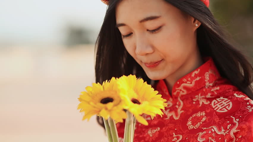 Beautiful Vietnamese girl in red traditional dress Ao Dai with yellow flowers. Close-up.