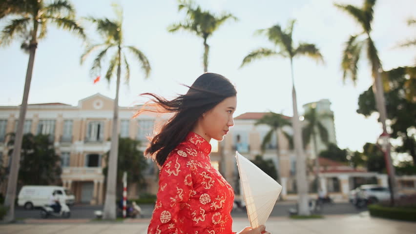 Vietnamese girl puts on a national cap Non La in the rays of the evening sunset in Da Nang