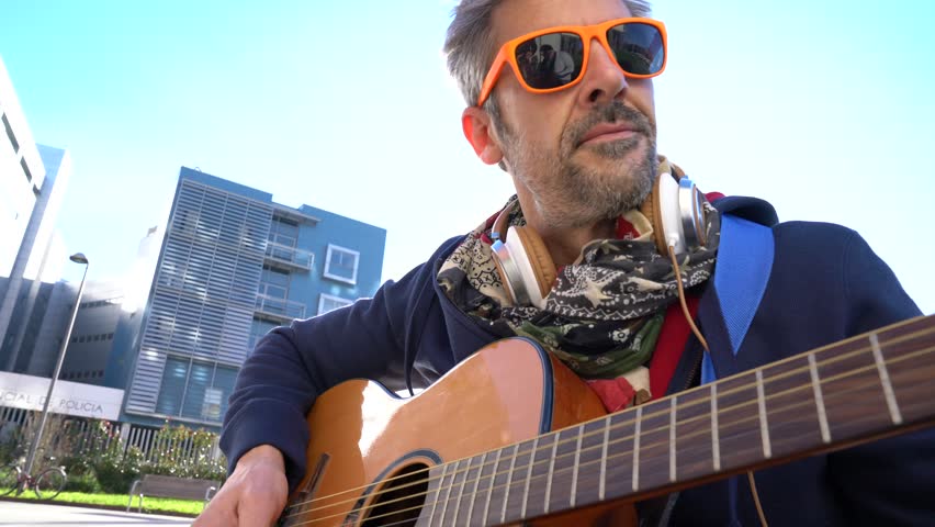Mature trendy guy playing the guitar in the street