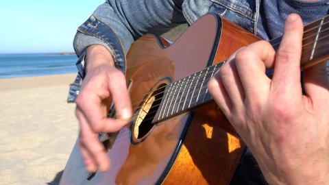 Closeup of man playing the guitar on the beach