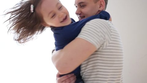 Young Father Hold In Arms Hug And Spin With Little Child Daughter By Bright Window At Home