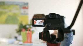 Woman preparing hand-made object cuisine fashion decorations gifts on table with professional video camera in the foreground filming the experience of the influencer vlogger