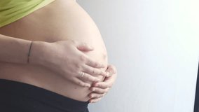 Pregnant woman caressing her tummy on black background