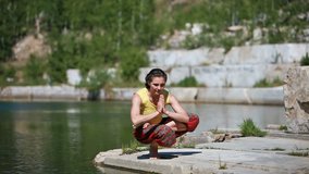 Positive young woman doing a sequence of asanas near the water