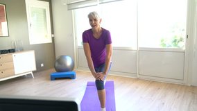 Senior woman doing fitness exercices in front of tv