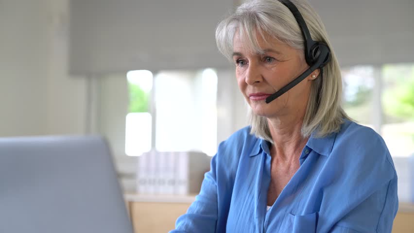 Senior woman in telemarketing department with headphones