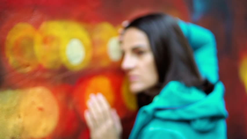 Thoughtful woman leaning on colorful wall, steadycam show, slow motion shot at 240fps
