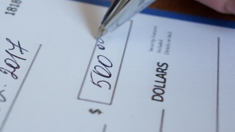 Writing a check for payment with a ballpoint pen. 