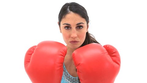 Serious woman using boxing gloves against a white background