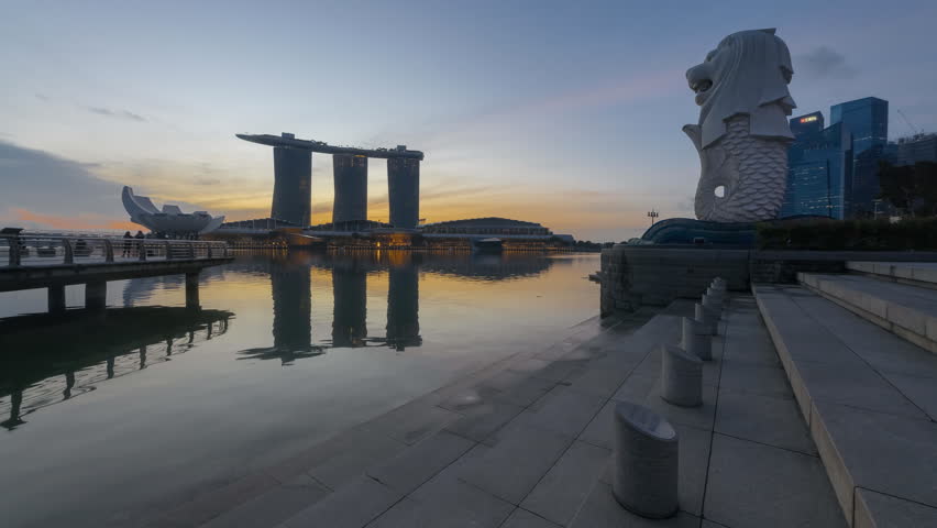 Beautiful and clear night to day time lapse of Singapore cityscape with the Merlion statue during sunrise at Marina bay quay, Singapore. 4K UHD, Motion Timelapse Slow Slide from Left to Right Royalty-Free Stock Footage #23669791