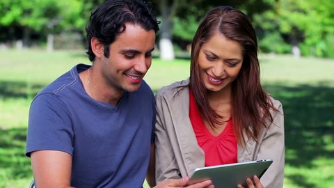Happy couple holding a tablet computer in a parkland