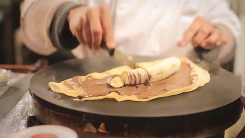Chef hands making traditional chocolate crepe in Paris 