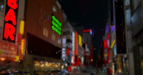Red light district with strip bars and flashing signs with rain down a window in front. Mocked up image.
