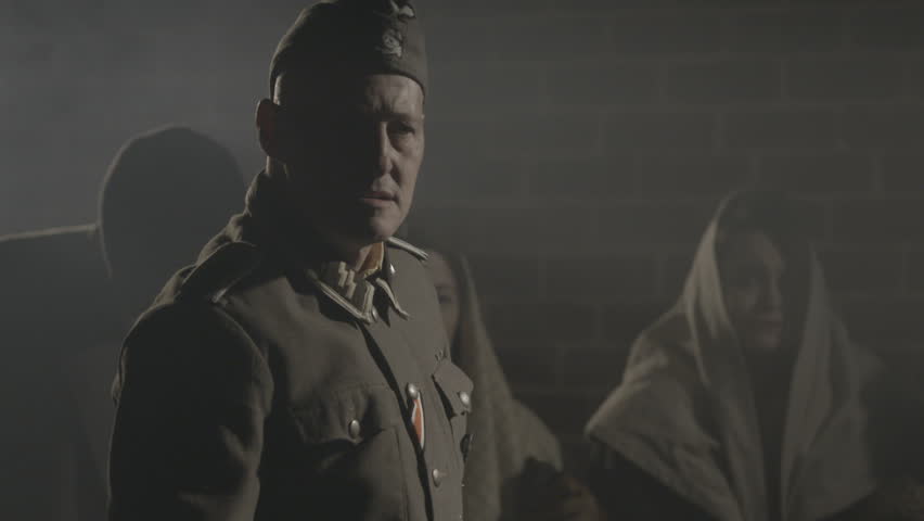 EUROPE - APRIL 2015 - Moody and edgy epic WW2 Re-enactment, recreation -- Nazi SS Soldiers round up Civilian prisoners in Europe in 1930s, 1940s and search then march onto trains with steam and night 