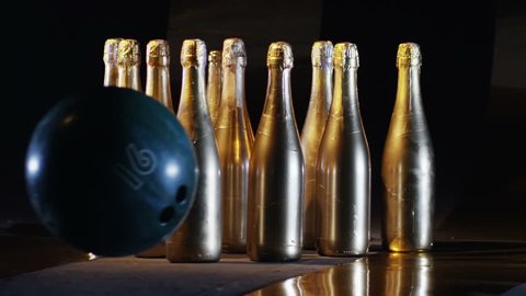 Bowling ball rolling and braking the golden bottles of champagne, puted like ninepins. Shot on RED HELIUM Cinema Camera in slow motion 250fps. 