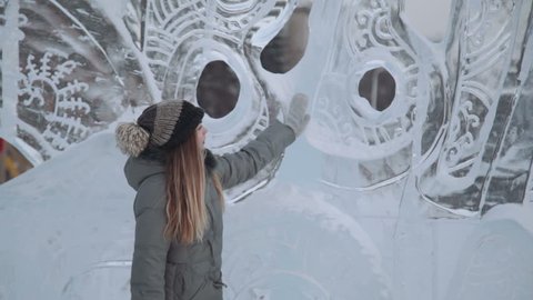 young woman smiling at the ice sculptures, winter gloves