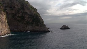 small rocky island low on positano coast with waves crashing
