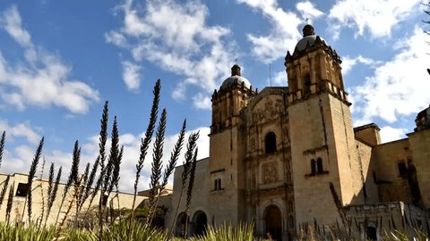 Cathedral of Santo Domingo in Oaxaca, Mexico,  view in perspective of the facade of the church with two bell tower and clouds that run behind the blue sky, time lapse