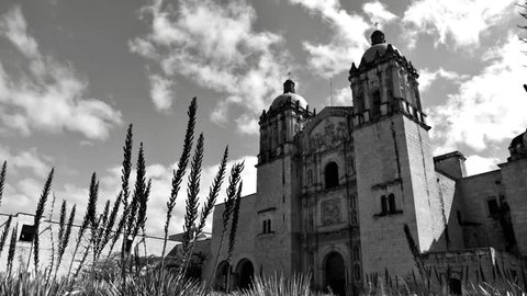 Cathedral of Santo Domingo in Oaxaca, Mexico,  view in perspective of the facade of the church with two bell tower and clouds that run behind the blue sky, time lapse Black and white