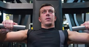 Man in gym doing press push weight exercise 4k close-up video. Male training chest muscles using exercise machine for body mass. Workout and bodybuilding sport concept