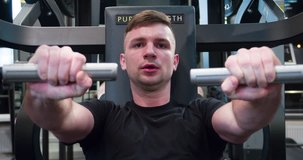 Man in gym doing press push weight exercise 4k close-up video. Male training chest muscles using exercise machine for body mass. Workout and bodybuilding sport concept