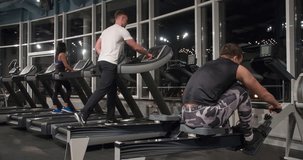 Group of fitness peoples training in gym 4k video. Men and woman runs and walks on treadmill and other exercise machine. Athletes in cardio and weight loss workout