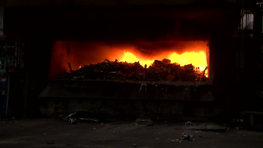 Aluminium foundry furnace loaded with metal. red hot flames glowing. liquid melting