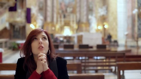 Believing woman kneeling in church prays
