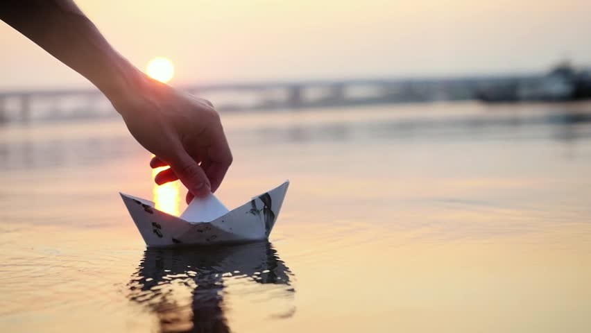 Man's hand putting paper boat on the water and pushing it away during beautiful sunset with reflection sun in the sea in slowmotion, as in childhood.. 1920x1080 | Shutterstock HD Video #23722702