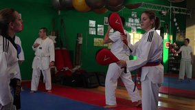 Slow motion video of an adult taekwondo training session in the gym, kicking, selective focus