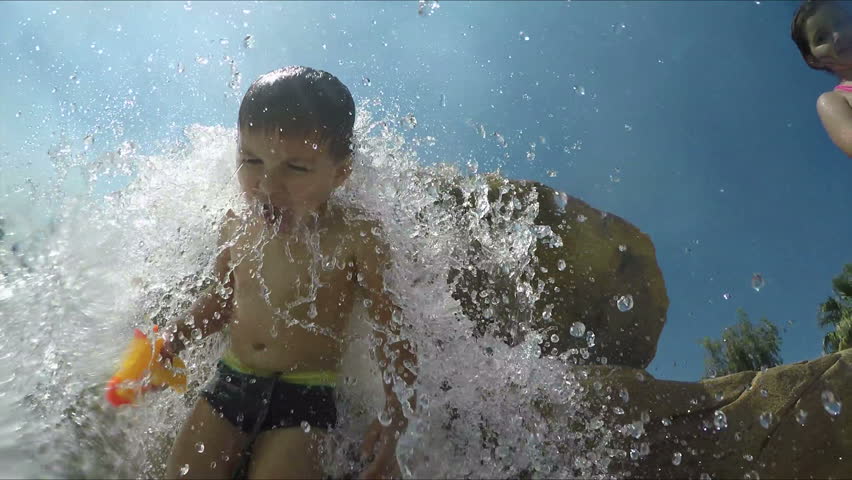 Little beautiful boy stands under water jets waterfall