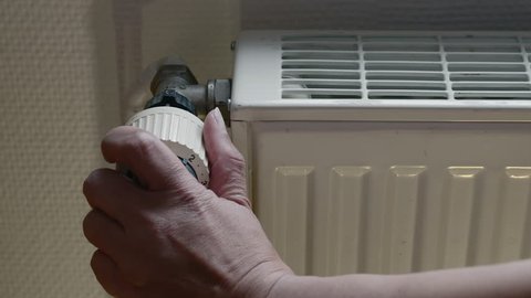 Woman Hand Adjusting The Temperature By Thermostat, Germany, Jan. 2016. tracking shot