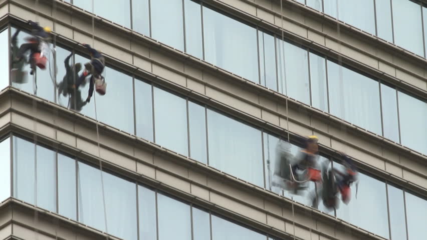 Climber cleaning modern building glass wall