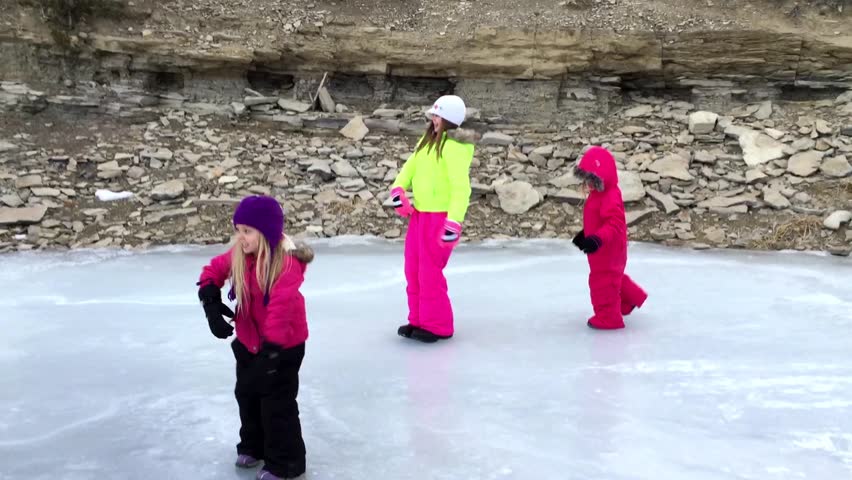 Three girls play and spin on a frozen lake.
