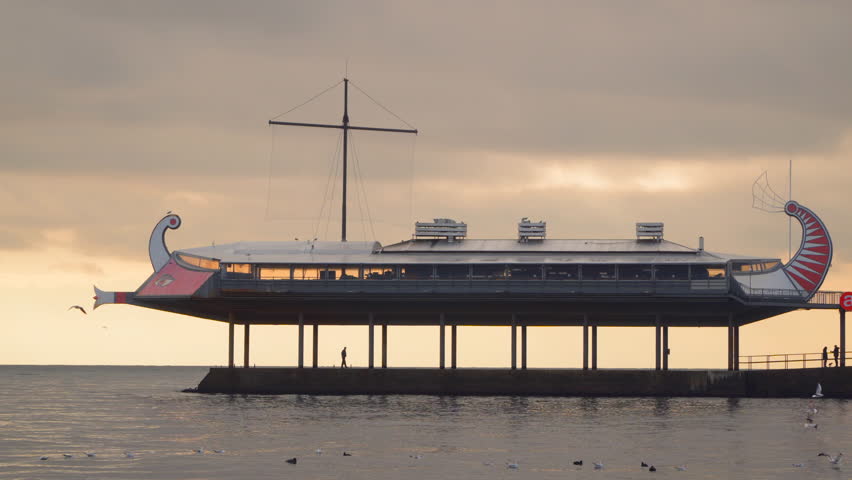 Restaurant in form of a ship in the sea against the evening sky.