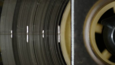 Old retro audio recorder reel spinning slowly. 4K, static macro shot. Seamless loop. Close up of audio cassette tape in use sound recording in a cassette player
