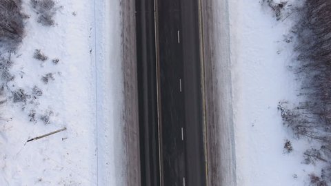 Camera flying over three lanes highway at winter season. Cars are on road. Russia. Top view from drone Arkivvideo