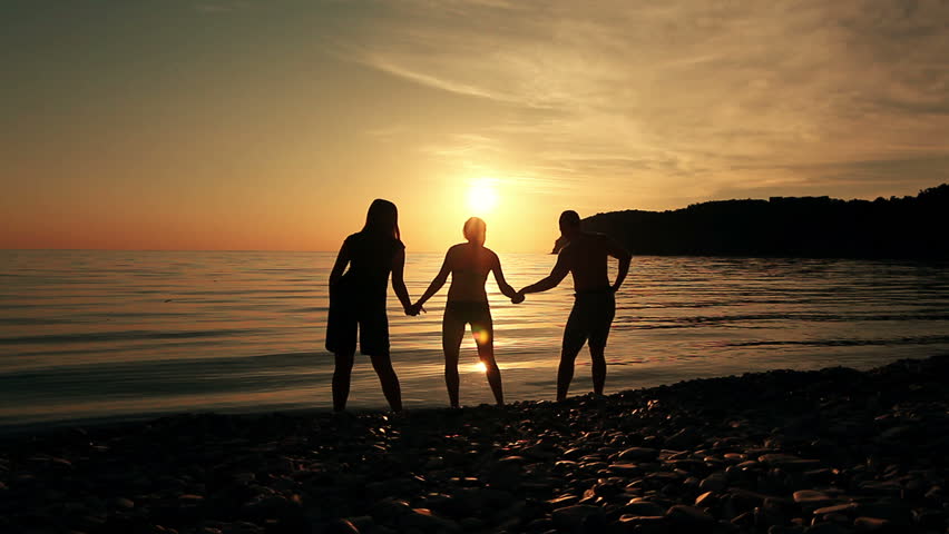 Group of people dancing on the beach at sunset. Man and women dancing  on the