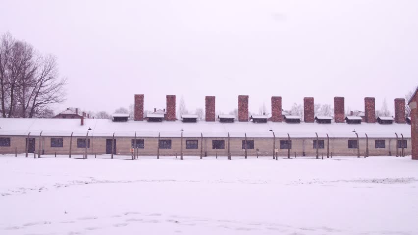 Steadicam shot of concentration camp building in falling snow. 4K clip