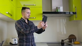 Man chatting on tablet computer in kitchen