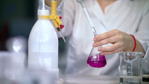 Scientist working with chemical reaction in chemistry lab. Chemical reaction in glass flask. Lab worker doing chemical experiment in laboratory