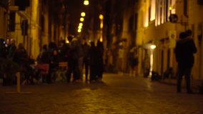 People on the night street of Rome near bars, unfocused video