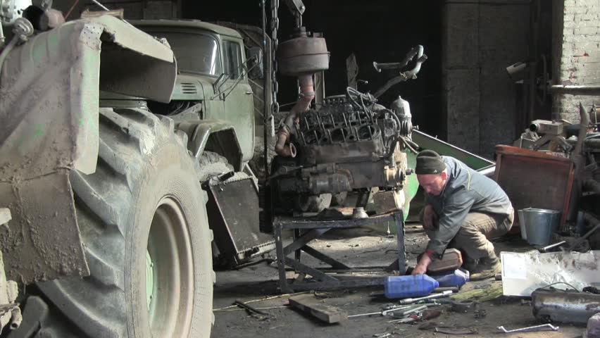 An auto mechanic works with old car