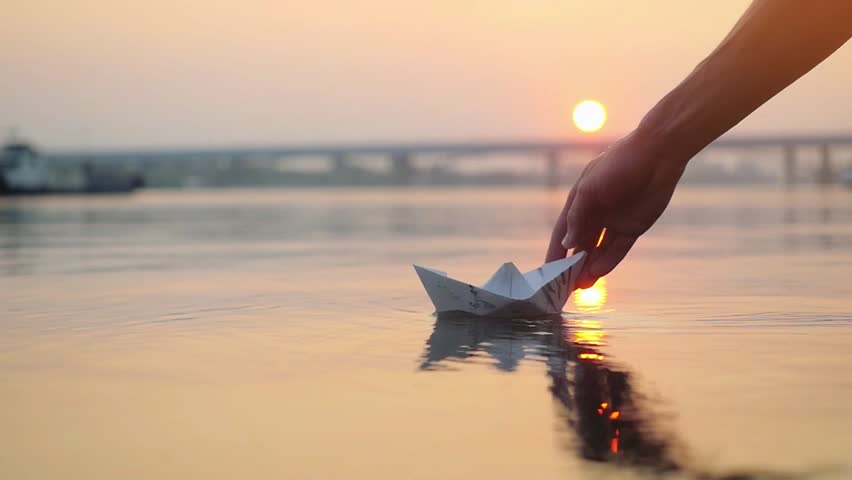 Man's hand putting paper boat on the water and pushing it away during beautiful sunset with reflection sun in the sea in slowmotion. 1920x1080 | Shutterstock HD Video #23783581