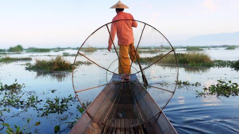 Inle Lake fisherman rowing boat in traditional style at sunrise, Shan State, Myanmar (Burma).