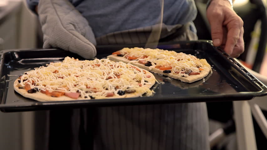 the man in glasses puts in the oven pizza